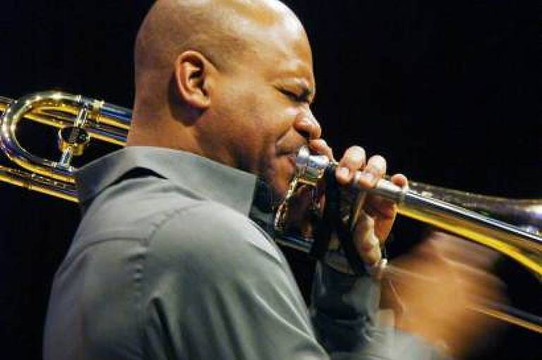 Em foto colorida, o trombonista norte-americano Robin Eubanks aparece tocando trombone