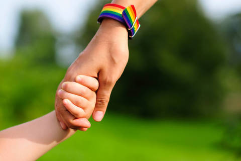 Parent holds the hand of a small child. mother holding baby's hand. rainbow lgbt bracelet on parents hand. - (Photo: Olga/Adobe Stock) DIREITOS RESERVADOS. NÃO PUBLICAR SEM AUTORIZAÇÃO DO DETENTOR DOS DIREITOS AUTORAIS E DE IMAGEM