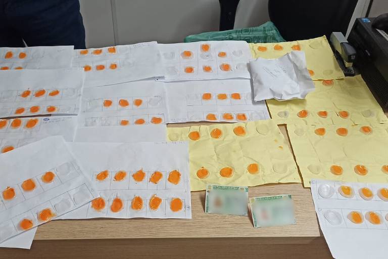Sobre uma mesa, duas cédulas de identidade e vários moldes de silicone em cor laranja, possivelmente utilizados para burlar sistema de biometria em autoescola