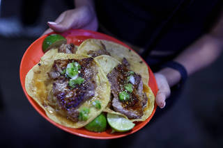 A woman shows her tacos at the Michelin-starred Taqueria El Califa de Leon, in Mexico City
