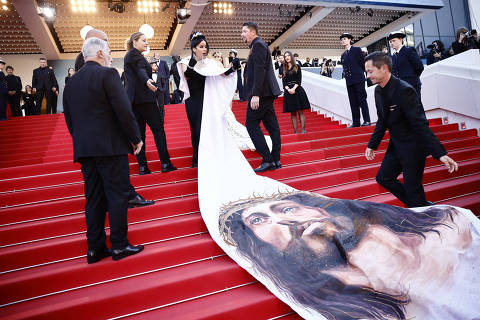 A guest wearing a dress depicting Jesus Christ poses on the red carpet during arrivals for the screening of the film 