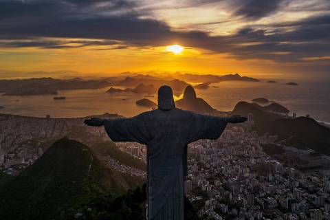The sun rises in front of the Christ the Redeemer in Rio de Janeiro, Brazil on March 29, 2023. (Photo by FLORIAN PLAUCHEUR / AFP)