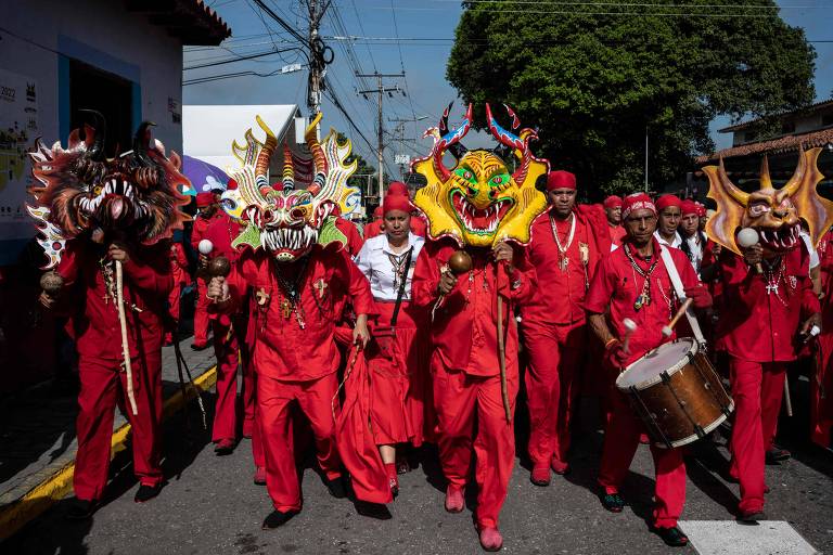 Homens vestidos com roupas tradicionais vermelhas, que se assemelham a diabos, dançam em procissão durante o feriado de Corpus Christi