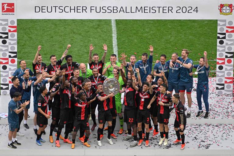 Jogadores do Bayer Leverkusen comemoram com o troféu, no estádio do time, a conquista da Bundesliga 2023/2024, sem perder nenhuma das 34 partidas
