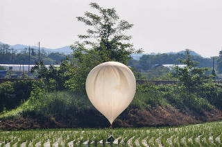 A balloon believed to have been sent by North Korea, carrying various objects including what appeared to be trash and excrement, is seen over a rice field at Cheorwon