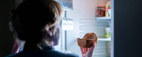 Mulher comendo bolo à noite na geladeira. (Foto: Rudenko/Adobe Stock )