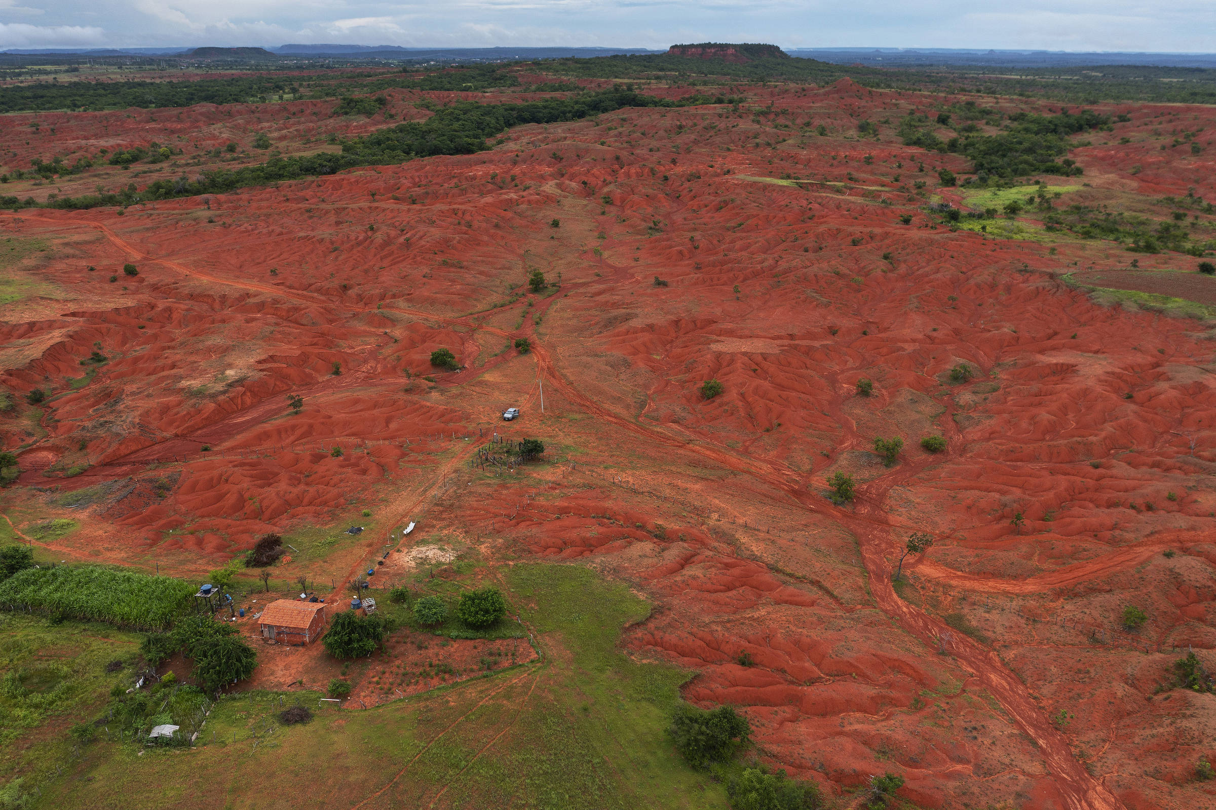 Vista aérea de área em processo de desertificação, exibindo terra vermelha  e imensas voçorocas