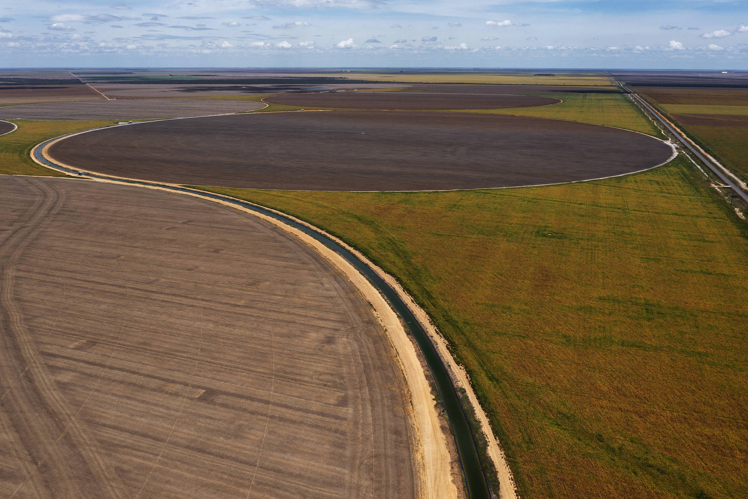Vista aérea de canal de irrigação que passa em meio a plantações de soja