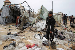 Palestinians inspect a tent camp damaged in an Israeli strike during an Israeli military operation, in Rafah