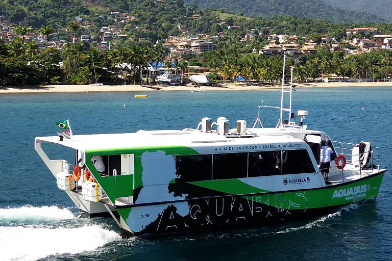 Barco branco, com a palavra Aquabus pintada em verde no casco, navega no mar 
