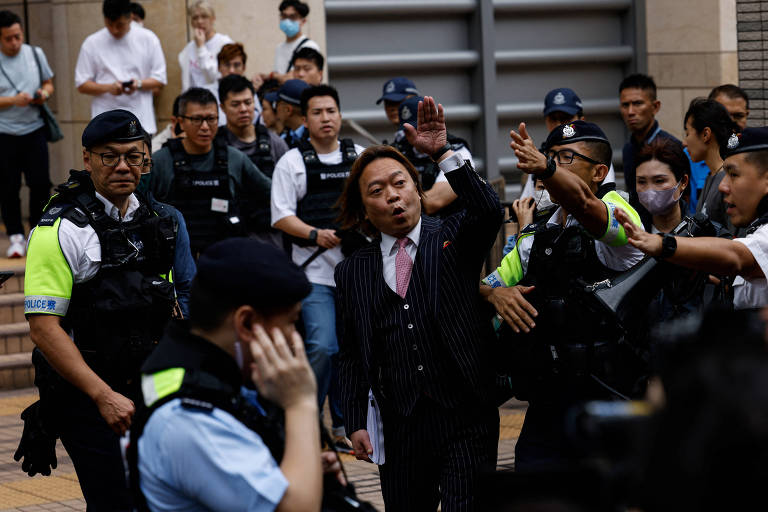 Lawrence Lau Wai-chung é escoltado pela polícia do lado de fora do prédio do Tribunal de Magistrados de West Kowloon depois de ser absolvido das acusações sob a lei de segurança nacional, em Hong Kong, China