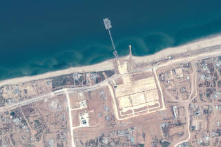 A satellite image shows an overview of trident pier and aid trucks, on the Gaza shoreline