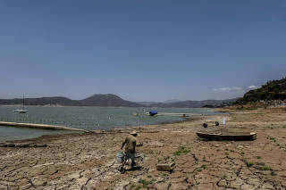 A fisherman on the shore of a lake that serves as a reservoir, so low that officials halted its use for water in April, in Valle de Bravo, west of Mexico City, April 12, 2024. (Cesar Rodriguez/The New York Times)