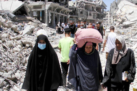 A woman carries belongings on her head, as Palestinians inspect the damage after Israeli forces withdrew from Jabalia refugee camp, following a raid, in the northern Gaza Strip, May 31, 2024. REUTERS/Mahmoud Issa ORG XMIT: LIVE