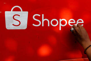 FILE PHOTO: A worker wipes the door of a car with the sign of Shopee, an Indonesian e-commerce platform, in Jakarta
