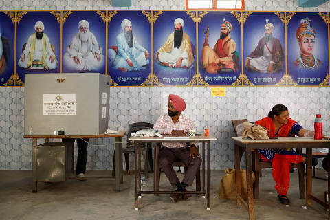 A man casts his vote as polling officials sit inside a polling station during the seventh and last phase of the general election, in Faridkot district, Punjab, India, June 1, 2024. REUTERS/Adnan Abidi REFILE - QUALITY REPEAT ORG XMIT: PPP-DEL204