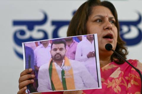 Congress spokesperson Supriya Shrinate shows a photograph featuring JD(S) MP Prajwal Revanna (L) who was summoned for alleged sexual abuse case, at a press conference in Bengaluru on May 1, 2024. (Photo by Idrees MOHAMMED / AFP)