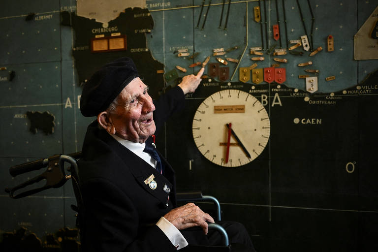 Veterano britânico George Chandler, 99, aponta para mapa em evento em Portsmouth