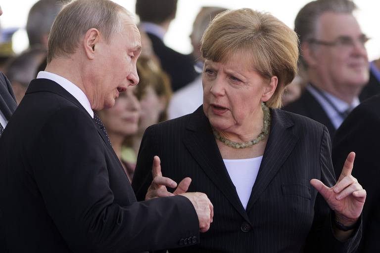 Putin e a então premiê alemã, Angela Merkel, conversam no evento dos 70 anos do Dia D