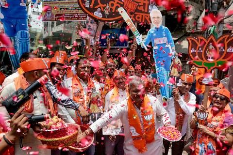 Supporters of Narendra Modi, India's Prime Minister and leader of Bharatiya Janata Party (BJP) carry his cut-outs as they celebrate vote counting results for India's general election in Varanasi on June 4, 2024. Vote counting was underway in India's election on June 4, with Prime Minister Narendra Modi all but assured a triumph for his Hindu nationalist agenda that has thrown the opposition into disarray and deepened concerns for minority rights. (Photo by Niharika KULKARNI / AFP)