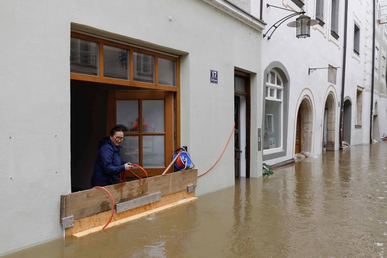 Mulher tenta bombear água com uma mangueira para fora de sua casa em Passau, Alemanha