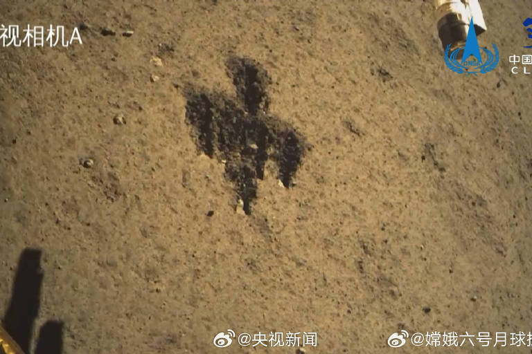 A imagem mostra a superfície marciana com marcas escuras deixadas pela movimentação de um rover. No canto superior direito, há símbolos e texto em chinês, indicando que a imagem é de uma missão espacial chinesa. A presença de elementos da sonda é visível no canto inferior esquerdo, sugerindo uma perspectiva de primeira pessoa da paisagem lunar.