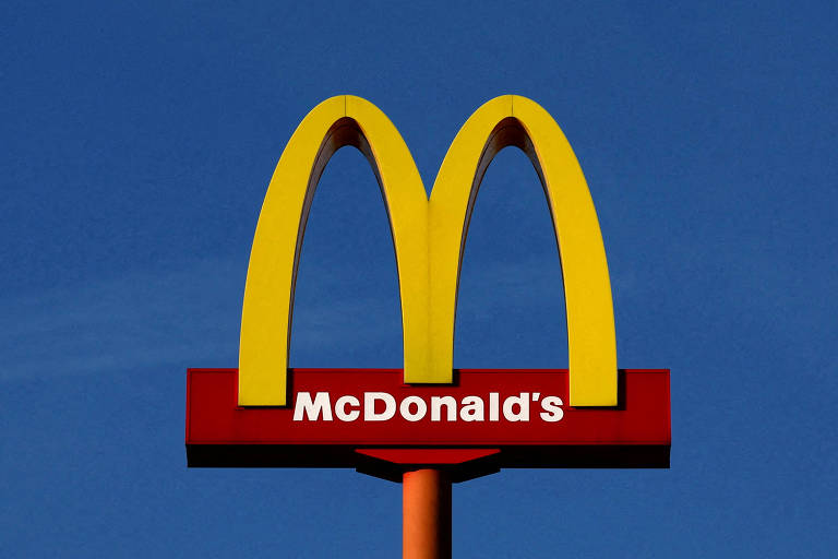 Letreiro do McDonald's se destaca contra um céu azul límpido, com arcos dourados.
