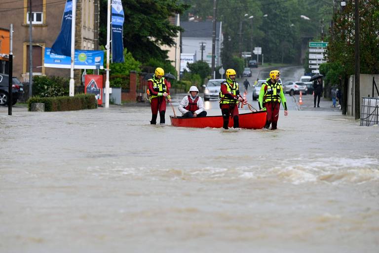 Bombeiros ajudam morador a atravessar uma estrada inundada em Bouzonville, França