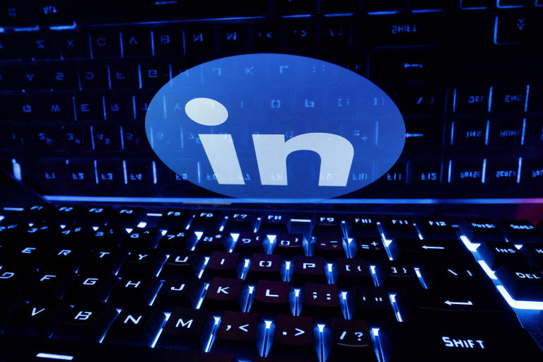 A imagem mostra um teclado iluminado em azul com o logotipo do LinkedIn projetado sobre ele, simbolizando a integração da tecnologia e das redes profissionais no ambiente de trabalho moderno.
