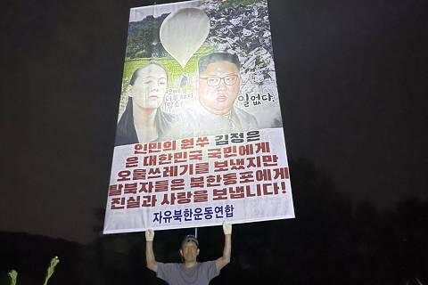 CORRECTION / This handout image provided by Fighters For Free North Korea, taken in Pocheon, Gyeonggi province, early on June 6, 2024, shows a South Korean activist from the group holding up a large poster, with photographs of North Korean leader Kim Jong Un and his sister and chief regime spokeswoman, Kim Yo Jong, with writing that translates as Enemy of the people Kim Jong Jun sent filth and trash to the South Korean people, but we the defectors send truth and love to our fellow North Koreans!