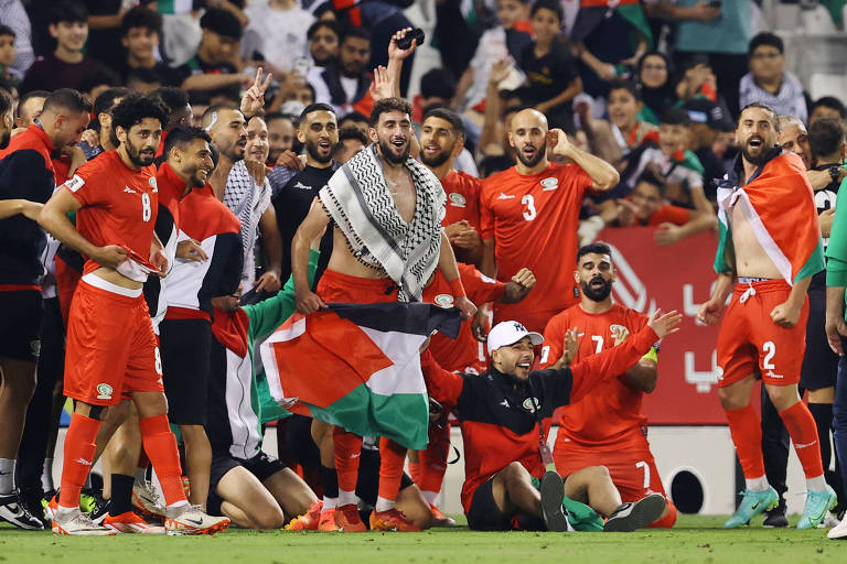 Jogadores da Palestina comemoram com a bandeira do país, em Doha (Qatar), a classificação para a próxima fase das Eliminatórias asiáticas para a Copa do Mundo de 2026