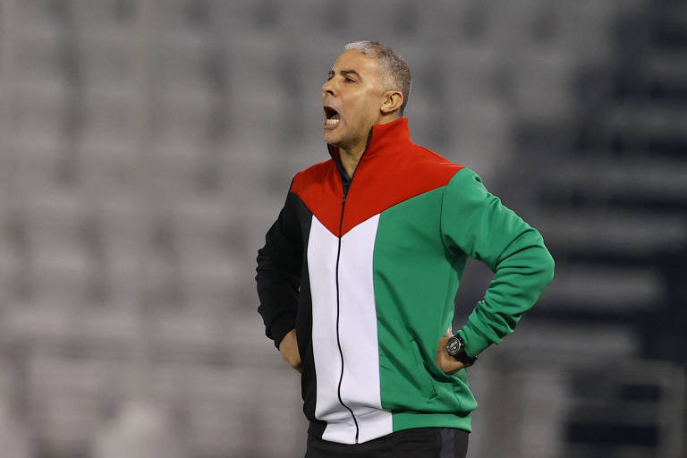 Usando agasalho nas cores verde, branca, vermelha e preta, o treinador da Palestina, Makram Daboub, orienta a seleção em jogo contra o Líbano, no Qatar