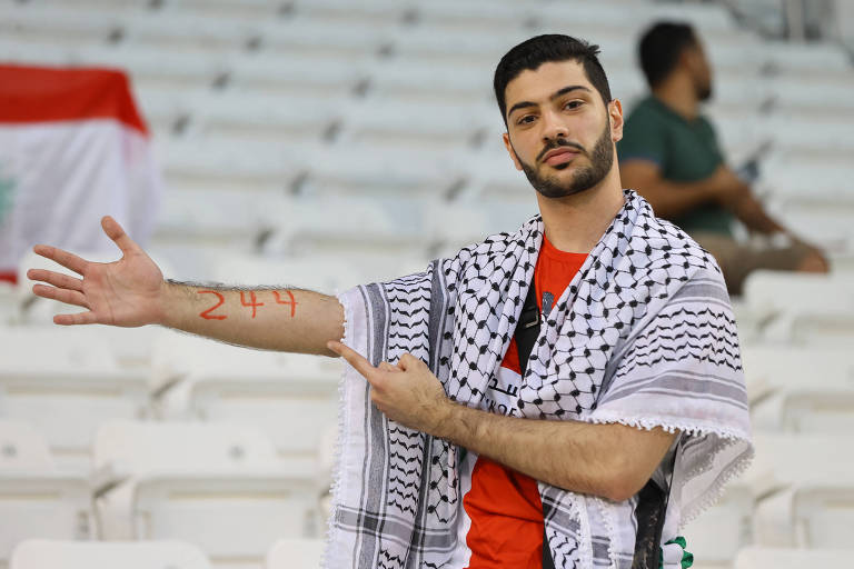 Torcedor em Palestina versus Líbano, em Doha (Qatar), mostra o número 244 em seu braço, referente ao número de dias desde o início da Guerra Israel-Hamas