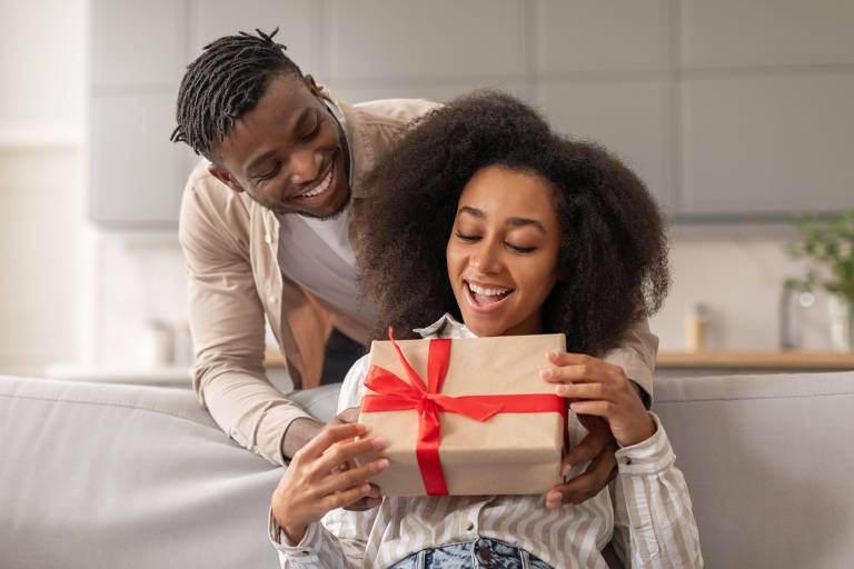 Um casal de um homem e uma mulher negros trocas presentes em uma sala de estar