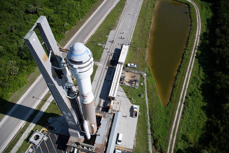 Uma visão aérea captura o momento de preparação de um foguete espacial, cercado por estruturas de suporte
