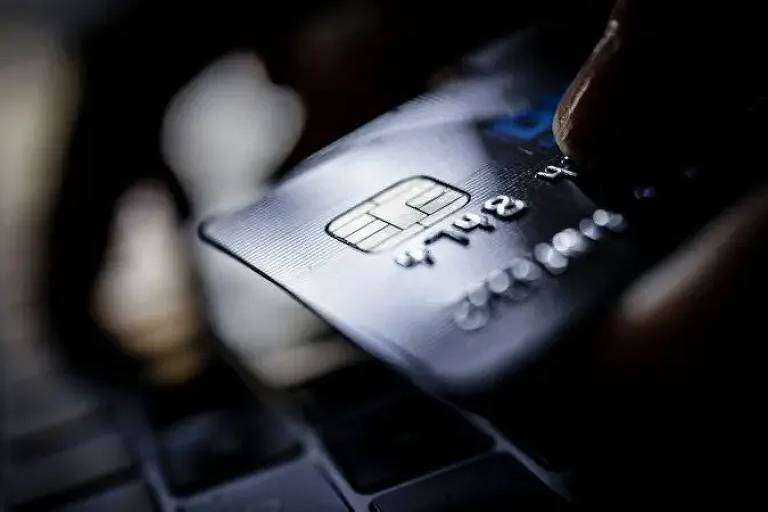 Um cartão de crédito sobre um teclado de computador, iluminado por uma luz suave