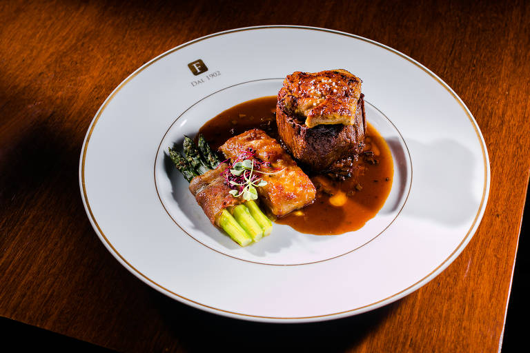 Prato em cima de uma mesa de madeira traz um prato com carne chamado filé rossini, um filé-mignon ao molho de vinho marsala com trufas negras e foie gras