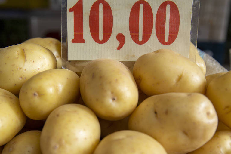 Batatas em um saco branco, com cartaz branco em que estão escrito 10,00 em vermelho