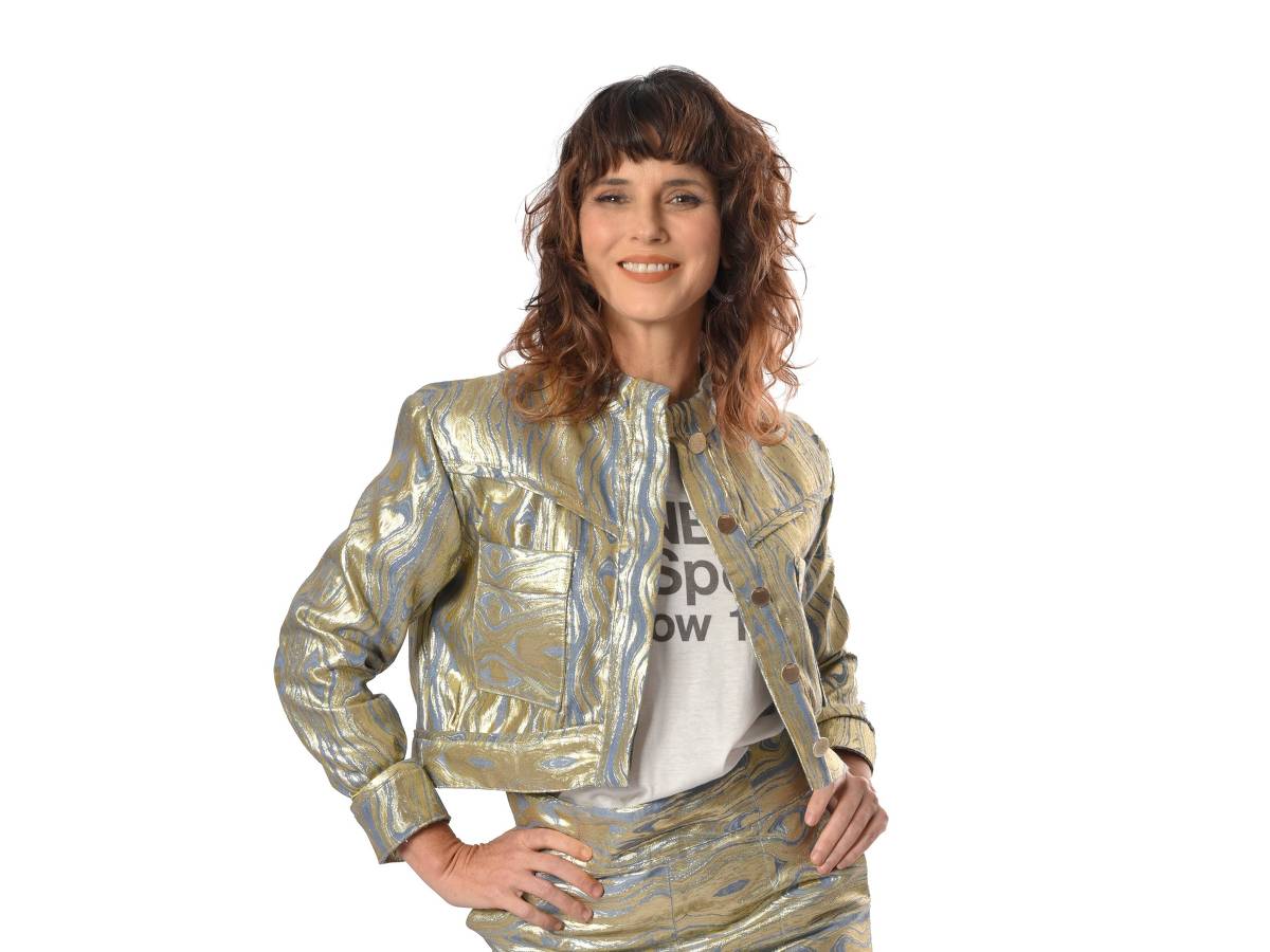 Helena Rizzo *** Local Caption *** Uma mulher exibe confiança e estilo em um conjunto metálico dourado, composto por uma jaqueta texturizada e uma saia lápis com fenda, complementados por uma camiseta casual e sandálias de salto alto douradas.