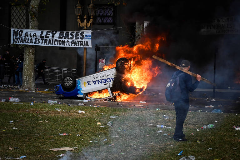 Carro de rádio argentina incendiado durante ato ao lado de fora do Congresso, em Buenos Aires, enquanto senadores debatem Lei de Bases