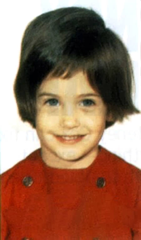 Uma criança posa para uma foto. Seu cabelo castanho é cortado em um estilo bob, e ela veste uma blusa vermelha com botões visíveis