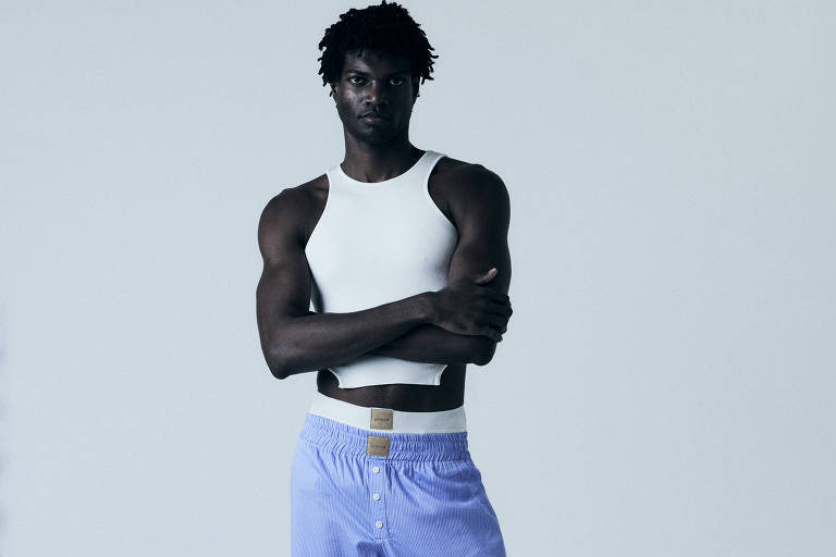 Modelo usa uma blusa curta que mostra parte de sua barriga e uma calça azul 