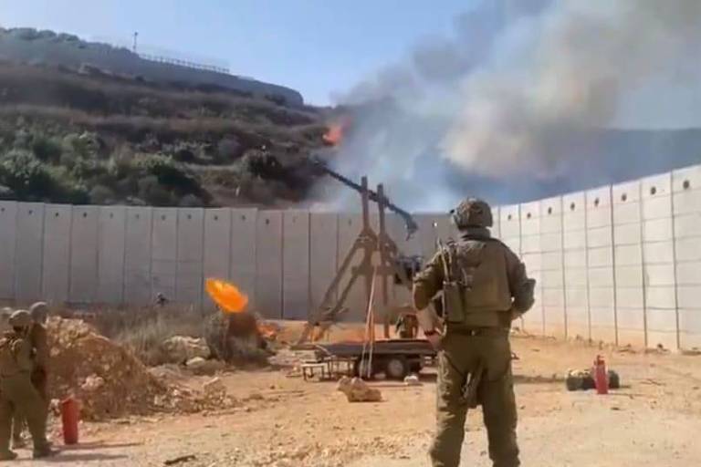 Imagem mostra soldados operando uma catapulta com uma carga pegando fogo ao lado de um muro