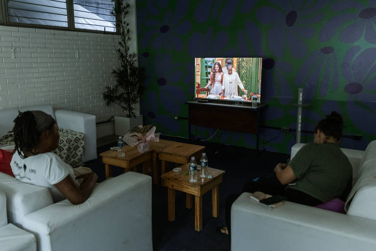 Mulheres assistem televisão em sala de descanso na Casa Violeta, uma casa de acolhimento para público