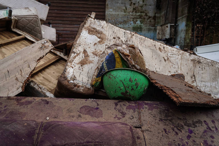 Escombros e capacete com bandeira do Brasil em bairro de Porto Alegre