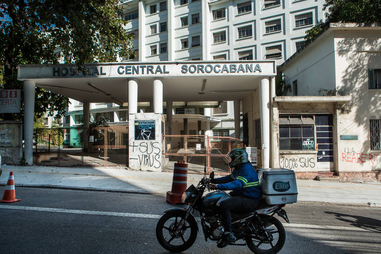 Moto passa na rua em frente à fachada do hospital