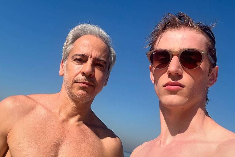 Dois homens sem camisa posam para uma selfie sob um céu azul