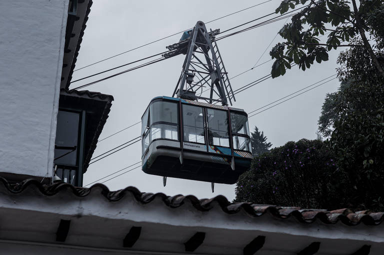 Teleférico quadrado, com paredes de vidro e hastes de metal, sobe até o topo do Cerro Monserrate, em Bogotá