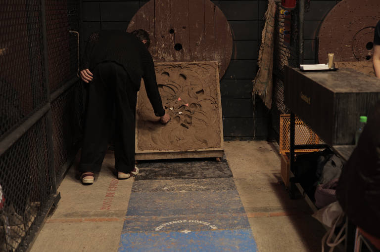 Homem retira um tejo, disco de metal usado em jogo homônimo, do tabuleiro de argila no final da pista de arremessos