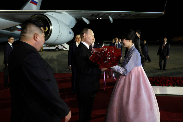 O presidente da Rússia, Vladimir Putin, recebe flores durante uma cerimônia de boas-vindas enquanto o líder da Coreia do Norte, Kim Jong-un observa, em  aeroporto em Pyongyang, Coreia do Norte